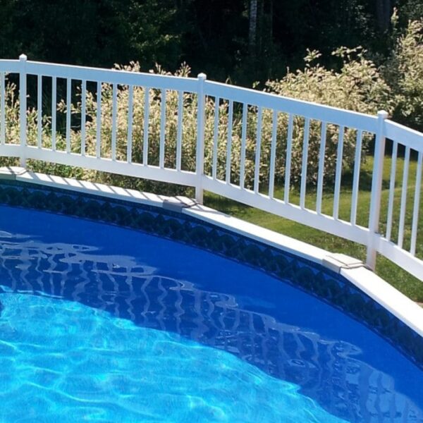 A partial view of a blue above-ground pool features the FENCE AG 24IN RESIN C WHITE VW surrounding it. Sunlight sparkles on the water, and green trees and bushes can be seen in the background.