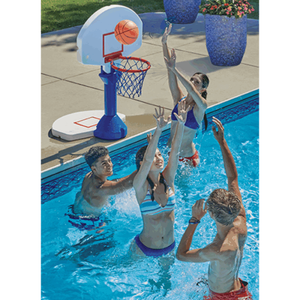 Four teenagers play basketball in a pool with the Dunk & Spike 2in1 Combo, reaching for the hoop as the ball goes through the net. Two large blue flowerpots are visible on the poolside in the background.