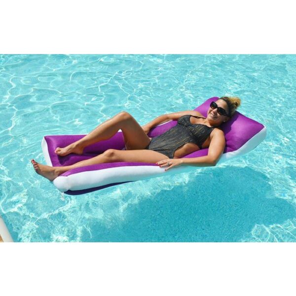 A woman in sunglasses and a black swimsuit lounges on the Aqua Cloud - Jelly, a purple and white pool float, smiling as she enjoys the sunny day in a clear blue swimming pool.