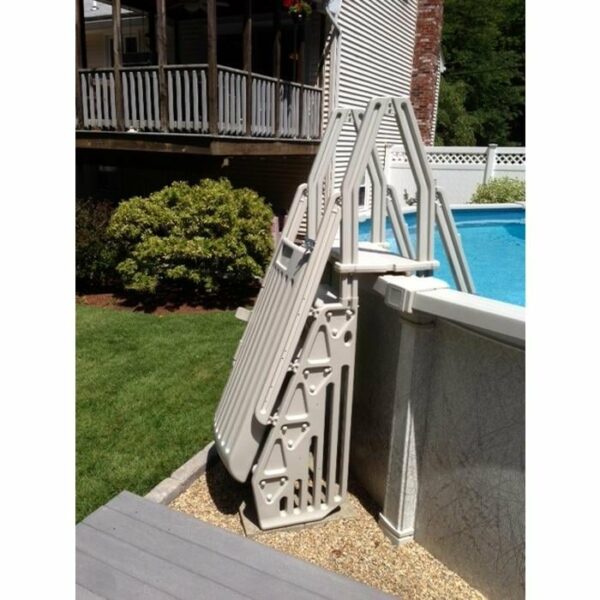 The Deluxe Step Entry with Gate is shown leaning against an above-ground pool, next to a wooden deck and landscaped yard in the background.
