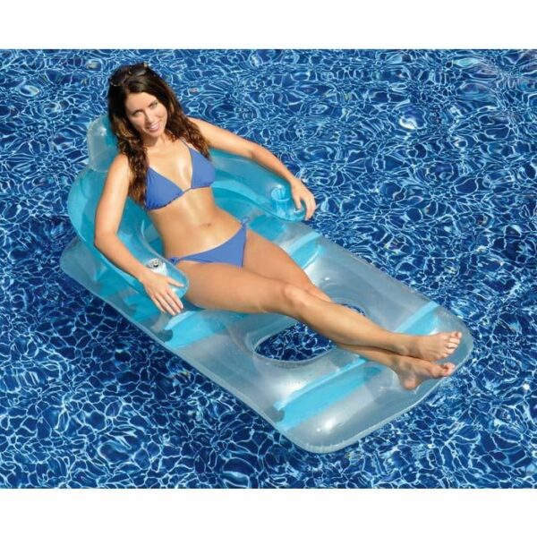 A woman in a blue bikini relaxes on the Deluxe Lounge Chair, a transparent inflatable seat, floating in a bright blue swimming pool with her legs outstretched and arms resting on the chair.