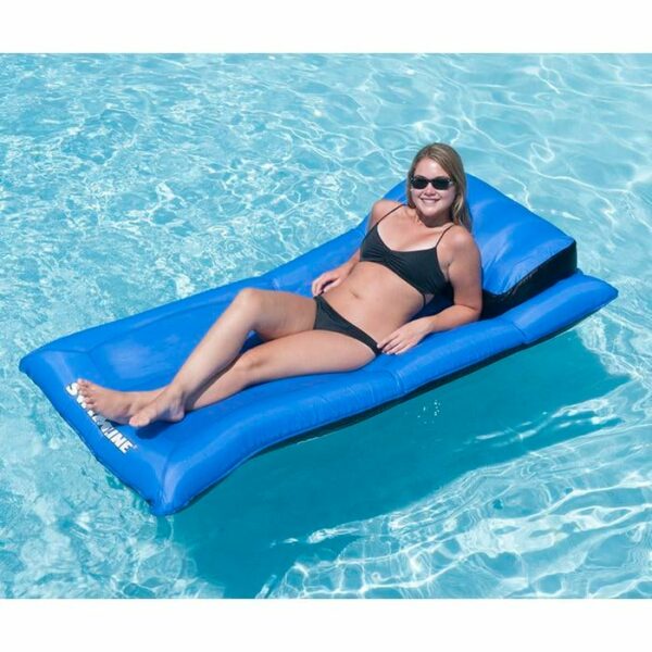 A woman in a black bikini and sunglasses relaxes on the Ultimate Super-Sized Floating Mattress, smiling as she lounges on clear blue water.