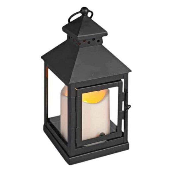 A small black metal peaked lantern with a glass door, featuring an LED resin candle light and timer, emits a warm yellow-orange glow.