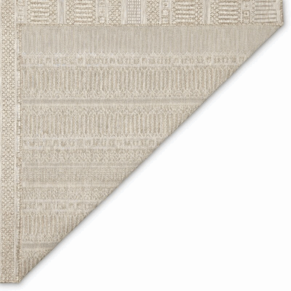 The Outdoor Rug-Striped Natural is shown in beige with geometric patterns of lines, dots, and rectangles in subtle neutral tones. One corner is folded over to reveal the textured underside.