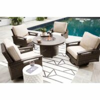 The Paradise Trail 5-Piece Chat Set features four cushioned wicker chairs around a round fire pit table on a geometric rug by the pool, with a side table for drinks and books amid lush green plants in the background.