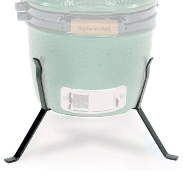 A close-up of the lower part of a green ceramic grill in a Nest for Mini Big Green Egg, supported by a three-legged black metal stand.