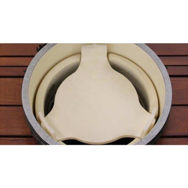 A close-up of the ConvEGGtor for Large Egg ceramic heat deflector plate inside a round grill, resting above a wooden surface.