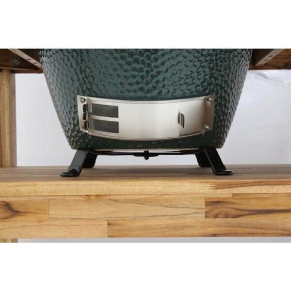 Close-up of the lower section of an XLarge EGG kamado grill, featuring a textured green surface, metal vent, and black Table Nest legs resting on a wooden table.