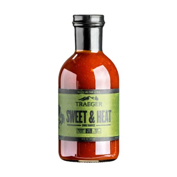 A glass bottle of Traeger Sweet & Heat BBQ Sauce, featuring a green label and black cap, filled with reddish-brown sauce and placed against a white background.