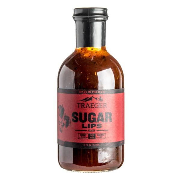 Traeger Sugar Lips Glaze comes in a clear glass bottle with a black cap and red label showing the product name. Inside, the glaze is rich brown with visible seasoning.