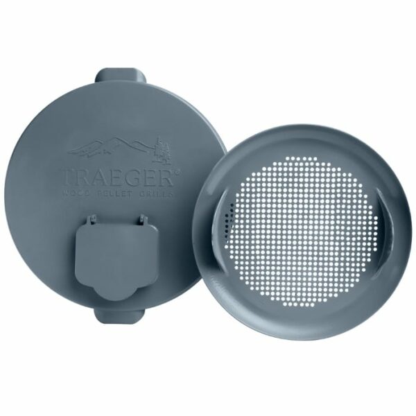 The Pellet Storage Lid & Filter includes two gray metal lids for a Traeger wood pellet grill: one solid lid with engraved branding and handle, and one perforated lid with small holes for ventilation.