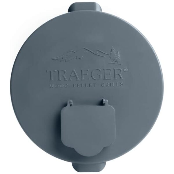 The Pellet Storage Lid & Filter is a round, gray plastic lid embossed with the Traeger Wood Pellet Grills logo, featuring mountain and tree designs, and includes a rectangular flap at the bottom edge.