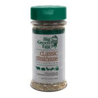 A clear plastic bottle of BGE-Classic Steak Seasoning with a green lid, 5.5 oz (156g), features the brand logo, product name, and meat icons on the label.
