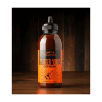 A bottle of Traeger Que Savory BBQ Marinade 16 oz. Squeeze Bottle with an orange label and black flip-top cap is shown on a wooden surface against a dark, blurred background.