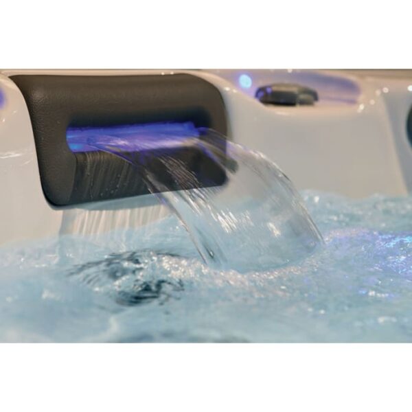 A close-up of the 533DL hot tub in Silver Marble Shell with Grey Cabinet, featuring a smooth water stream from a black spout into bubbling blue water, highlighted by soft blue lighting.