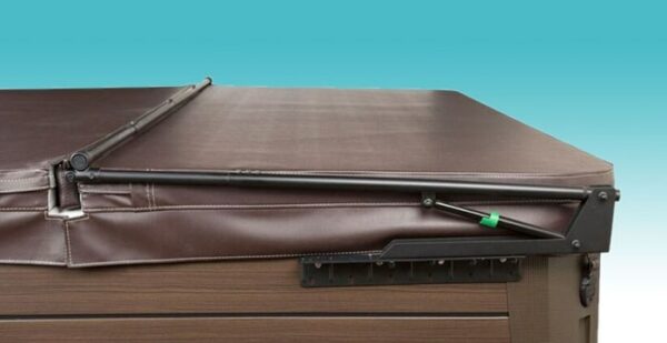A brown hot tub with a matching cover partially folded open, held by the Cover Lifter: Cover Valet Pros black metal arm, against a blue gradient background.