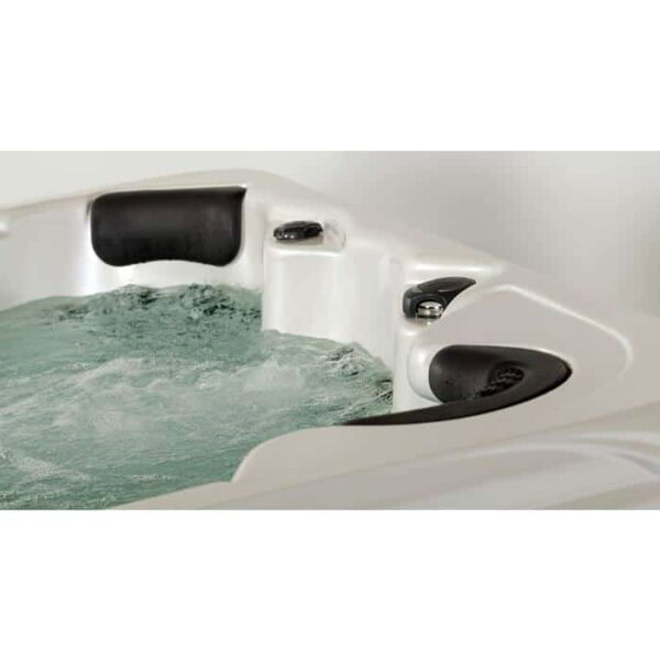 Close-up of the Kona hot tub in Smokey Mountain Shell with a Java Cabinet, filled with bubbling water, featuring two black cushioned headrests and built-in edge controls.