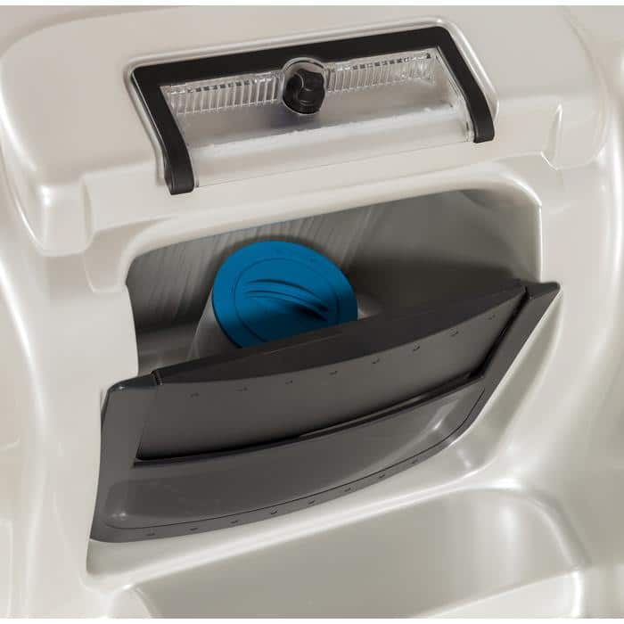 A close-up of a compartment in the Kona - Smokey Mountain Shell / Java Cabinet appliance, showing a partially open black lid revealing a blue filter or cap inside. Above it is a clear plastic window with a black knob.