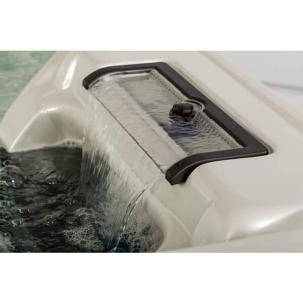 Close-up of the Lanai hot tubs waterfall feature: water flows smoothly over a white-framed, clear-panel waterfall with a black border into the bubbling Midnight Canyon Shell interior and Black Cabinet.