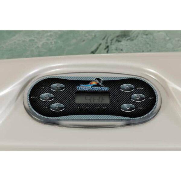 Close-up of a Lanai - Midnight Canyon Shell/Black Cabinet control panel on a hot tub, featuring buttons for jets, lights, temperature adjustment, and a digital display screen with water visible in the background.