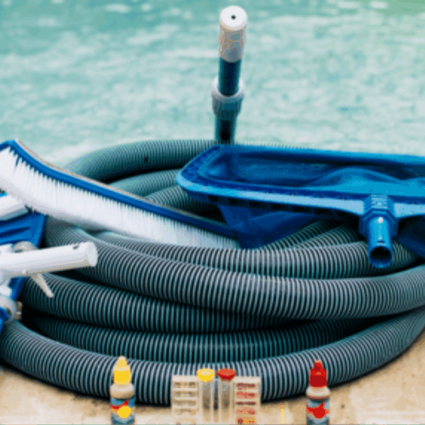 Close-up of Inground Pool Closing 2025 kit, featuring a hose, brush, net, water testing kits, and chemical bottles arranged on the poolside.