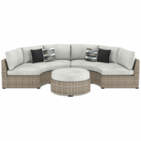 The Calworth Grouping 3-piece features a curved outdoor wicker sectional sofa with light gray cushions, a matching round ottoman, and four accent pillows—two solid dark gray and two patterned in gray, black, and white.