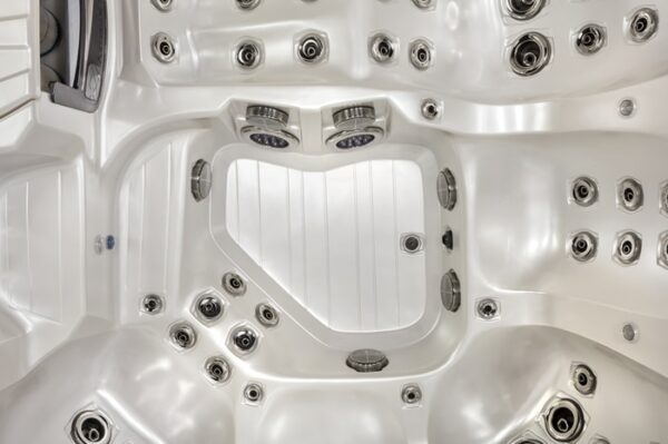 Top-down view of the Dove Canyon with Stereo hot tub in a White Pearl Shell/Smoke Cabinet, featuring multiple seating areas, numerous jets, and controls arranged around its smooth, contoured interior.