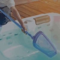 A person uses the Spa Opening to clean a hot tub, with a wooden deck and jacuzzi jets visible in the background.