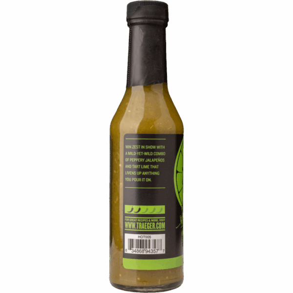 A bottle of Traeger Jalapeño & Lime Hot Sauce with a black cap and green label displays descriptive text, barcode, and website. The yellowish-green sauce inside hints at a blend of jalapeños and lime flavors.